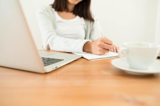 Femme écrivant sur le carnet de notes sur son bureau