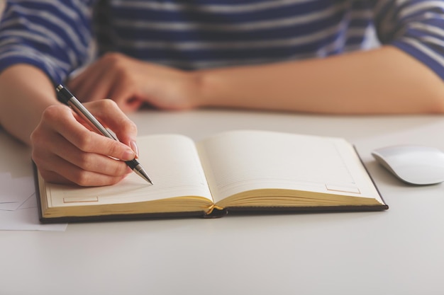 Femme écrivant dans un cahier à couverture rigide