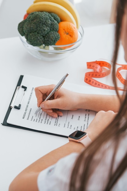 Femme écrivant des informations dans le bloc-notes Un travailleur médical professionnel en blouse blanche est au bureau