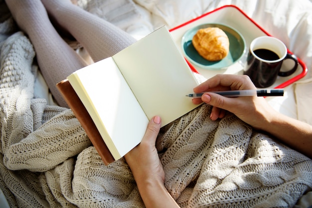 Femme écrivant un journal de cahier au petit déjeuner le matin