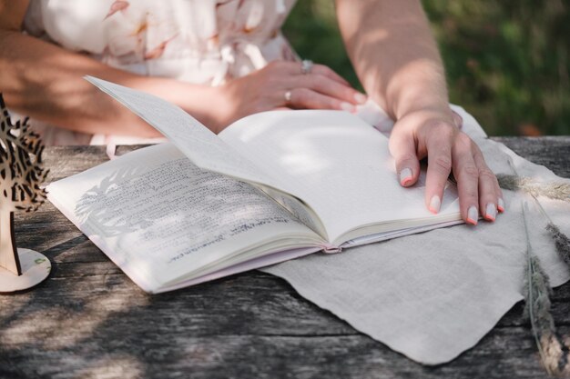 Femme écrivant, journal de lecture sur la table en bois. Souvenirs romantiques. Feuilletant un cahier, notes à l'extérieur dans le parc. Souvenirs,