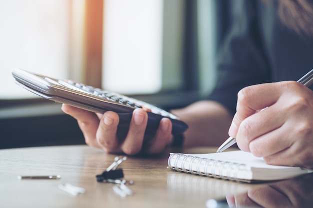 femme écrivant et utilisant la calculatrice