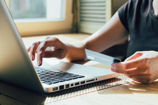 Une femme effectue un achat en ligne sur un ordinateur à l'aide d'un ordinateur portable et d'une carte de crédit