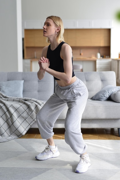 Femme effectue des exercices accroupis à la maison