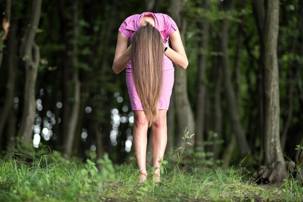 Une femme effrayante aux cheveux longs se pencha dans une forêt sombre et sombre.