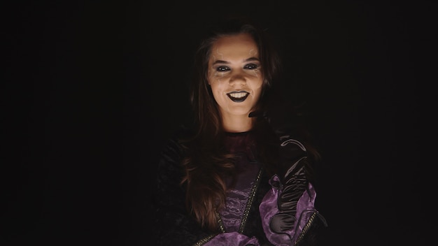 Femme effrayante habillée comme une sorcière pour halloween sur fond noir