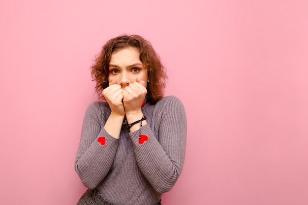 Femme effrayée dans un pull gris et aux cheveux bouclés