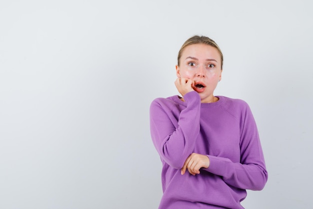 La femme effrayée met sa main sur la joue sur fond blanc