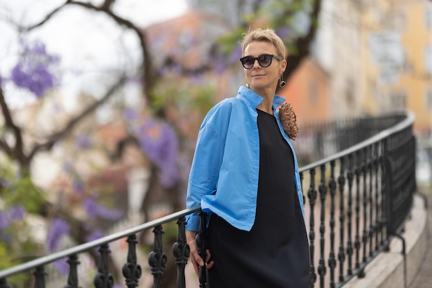 Femme élégante adulte portant des lunettes de soleil debout sur les escaliers dans le parc européen