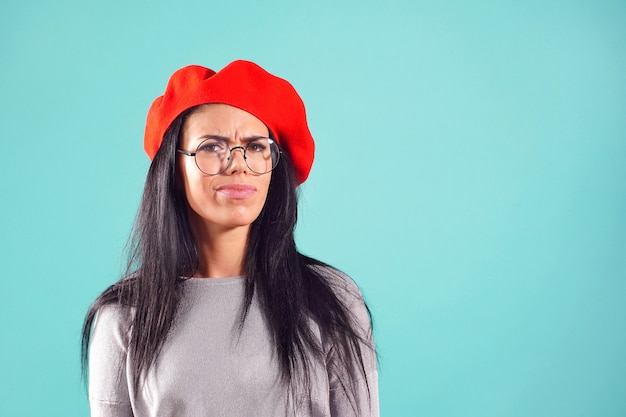 Femme élégante en béret rouge fronça les sourcils à la caméra