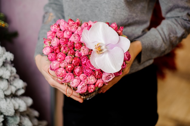 Femme élégante avec un bouquet de nombreuses petites roses et une grande orchidée