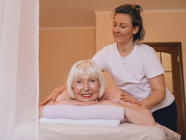 femme élégante caucasienne âgée aux cheveux gris et phalaenopsis rose dans ses cheveux au massage thaï