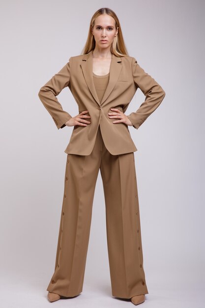 Femme élégante en costume marron beige pantalon boutonné veste sur fond blanc Figure mince