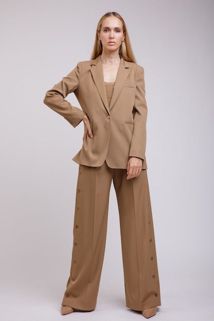 Femme élégante en costume marron beige pantalon boutonné veste sur fond blanc Figure mince