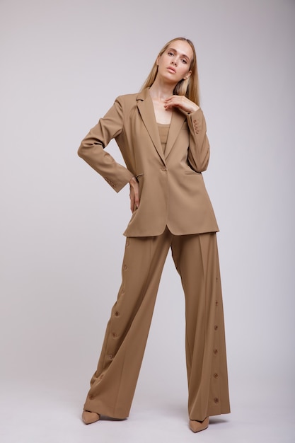 Femme élégante en costume marron beige pantalon boutonné veste sur fond blanc Figure mince