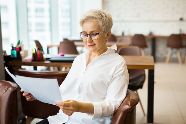 Femme élégante dans une chemise blanche tenant des documents