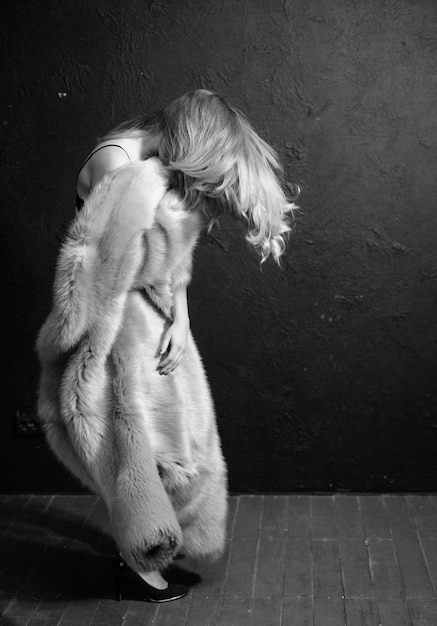 Femme élégante dans la lumière de studio de mouvement pointu de manteau de fourrure