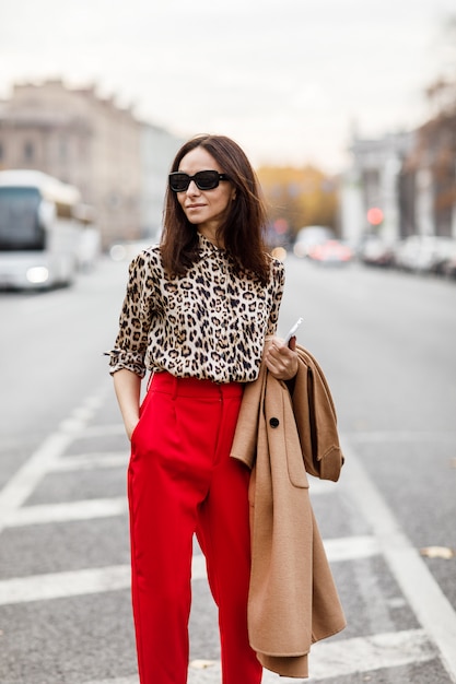 Femme élégante dans un manteau beige et un pantalon rouge