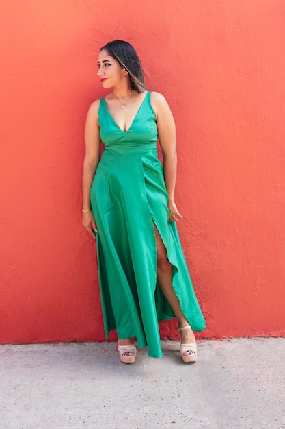 Femme élégante dans une robe verte à la mode dans la perspective d'un mur dans la rue