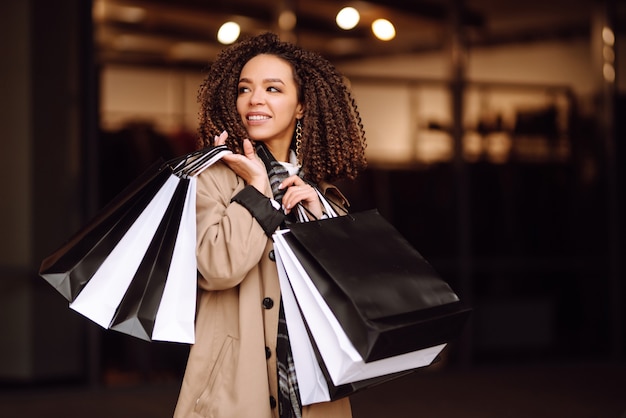 Femme élégante dans des vêtements à la mode avec des sacs à provisions près du centre commercial. Femme après le shopping.