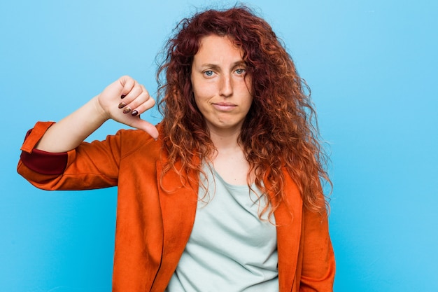 Photo femme élégante jeune rousse montrant un geste d'aversion, les pouces vers le bas. notion de désaccord.