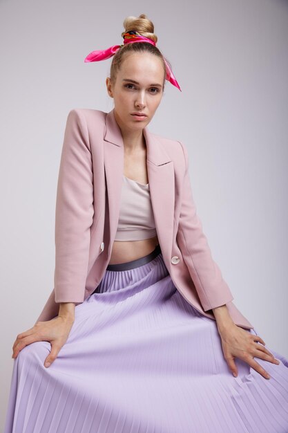 femme élégante en jolie veste rose pastel, jupe lilas sur fond blanc