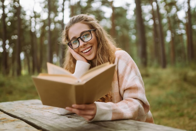 Une femme élégante lisant un livre dans le parc d'automne