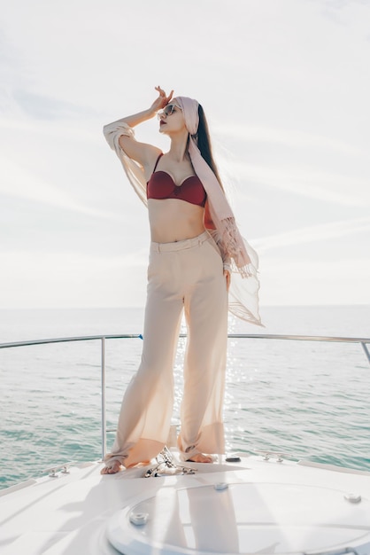 Femme élégante luxueuse en vêtements d'été posant sur un yacht au soleil partant en vacances