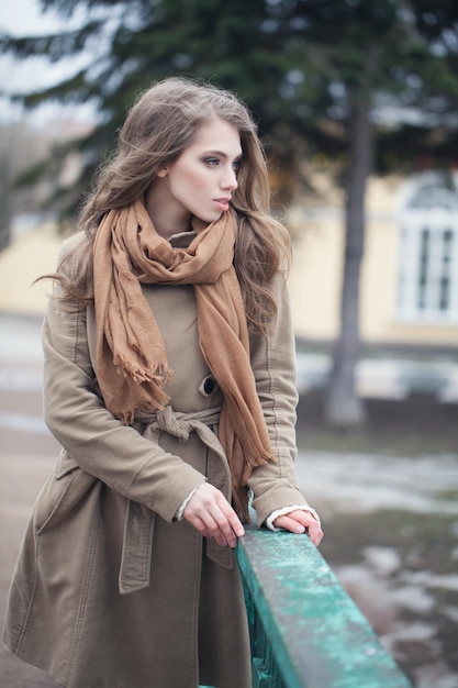 Femme élégante en manteau marron et écharpe en coton à l'extérieur