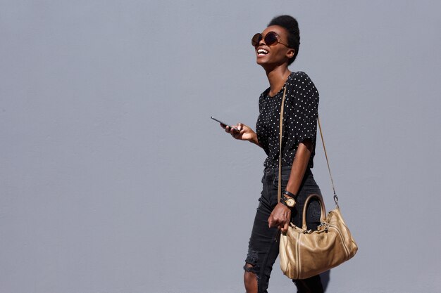 Femme élégante marchant avec sac et téléphone portable