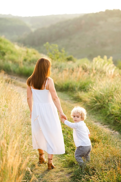 La femme élégante mène son fils par la main