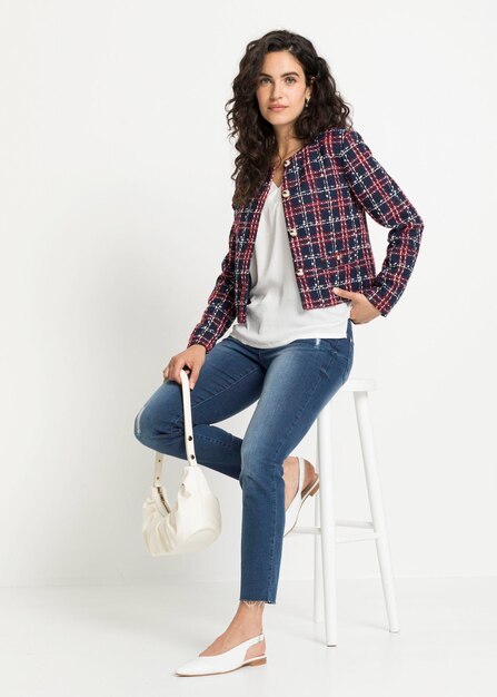 Une femme élégante et à la mode pose pour un groupe de vêtements sur un fond blanc