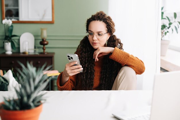 Femme élégante naviguant sur smartphone à la maison pour faire du shopping en ligne