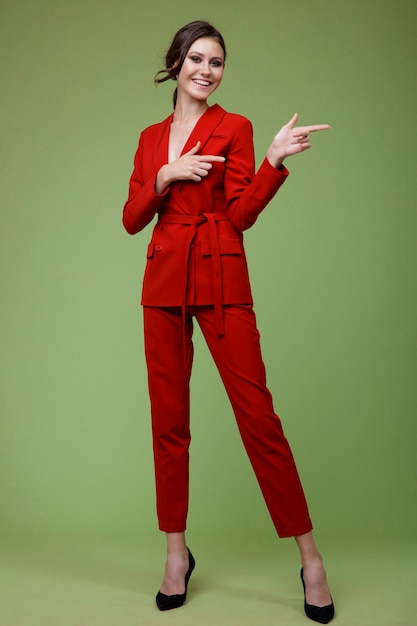 Femme élégante en pantalon veste de costume rouge sur fond vert Studio Shot Businesswoman