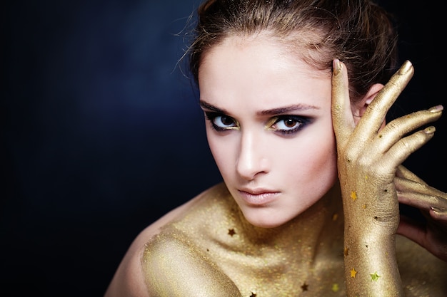 Femme élégante à la peau dorée et maquillage de fête glamour