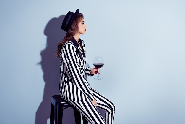 Femme élégante posant avec chapeau et verre à vin