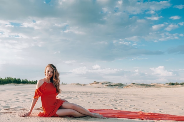 femme élégante posant sur la plage avec une robe rouge