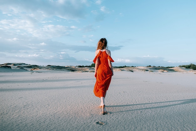 femme élégante posant sur la plage avec une robe rouge