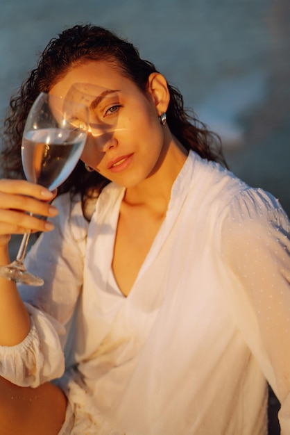 Femme élégante en robe blanche élégante posant près de la mer Heure d'été Week-end de voyage se détendre