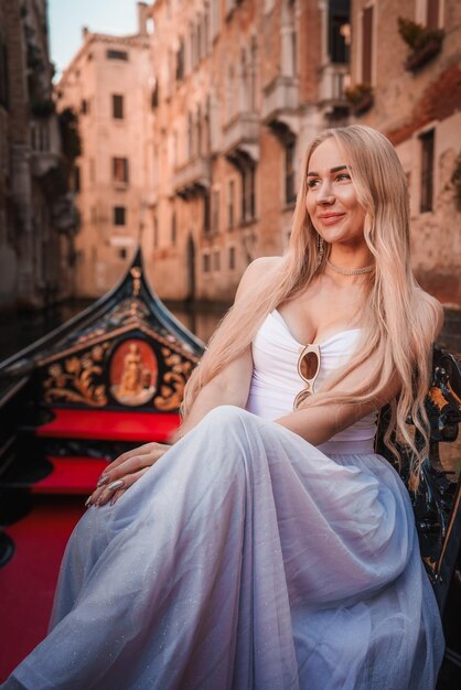 Femme élégante en robe blanche profitant d'un tour en gondole à Venise, en Italie, par une journée ensoleillée