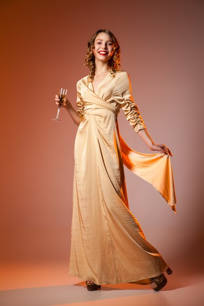 Femme élégante en robe dorée avec verre à vin