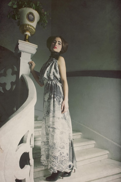 Femme élégante en robe longue dans les escaliers vintage