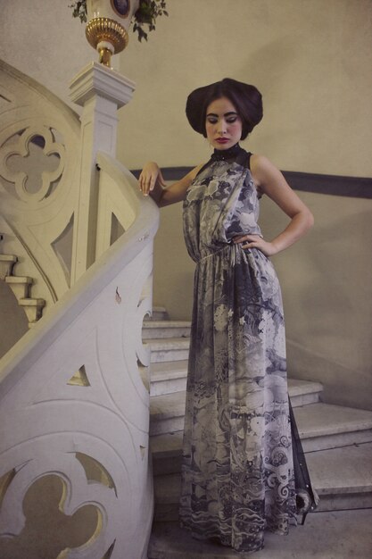 Femme élégante en robe longue dans les escaliers vintage