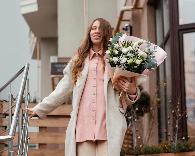 Femme élégante tenant un bouquet de fleurs à l'extérieur