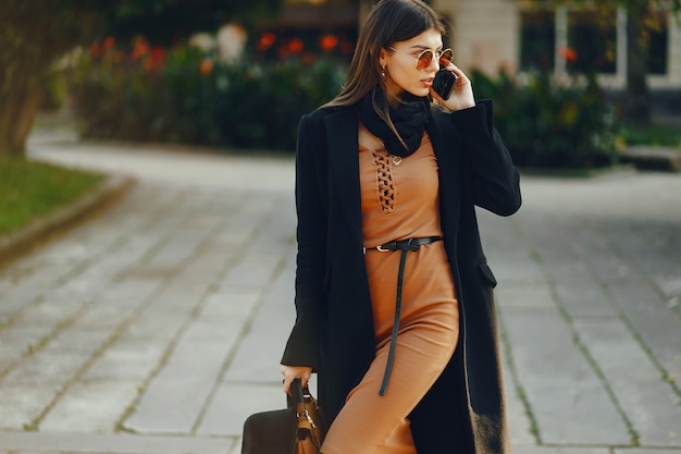 Une femme élégante utilise son téléphone portable lorsqu&#39;elle traverse la ville par une journée chaude et ensoleillée