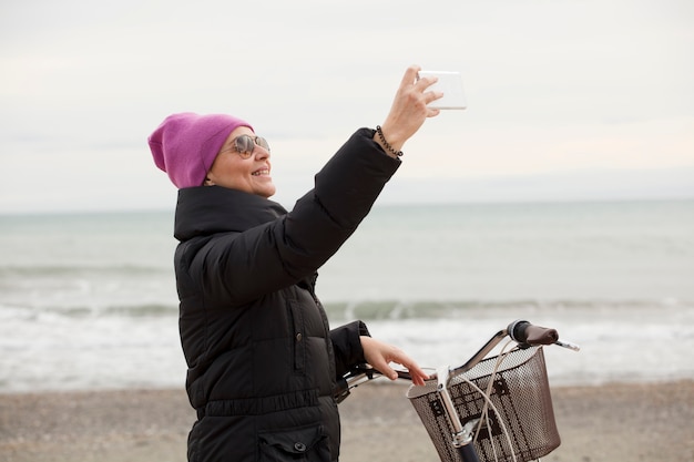 Femme élégante à vélo et à l'aide d'un téléphone portable. Près de la mer, espace pour le texte