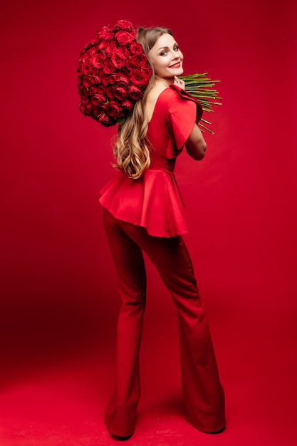 Femme élégante en vêtements rouges tenant des fleurs