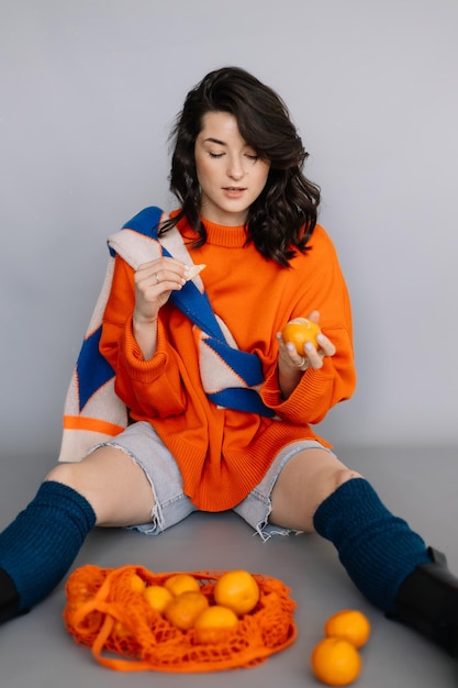 Femme élégante vêtue d'une veste en tricot orange posant pour une photo dans un studio photo