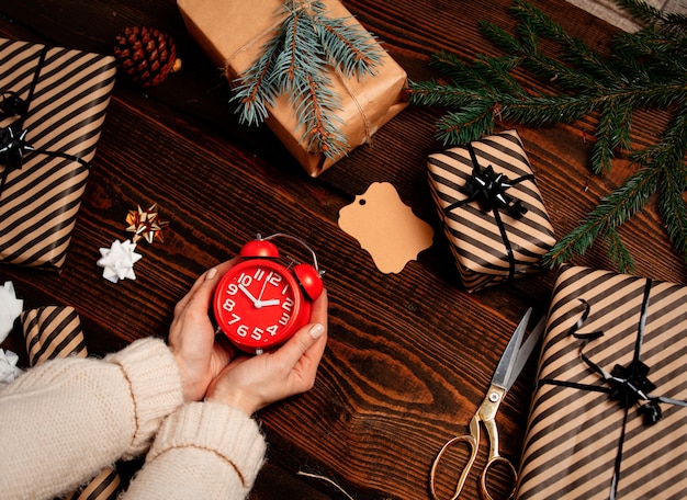 Femme emballant un réveil en cadeau sur une table