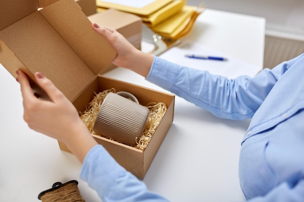 femme emballant une tasse dans une boîte aux colis au bureau de poste